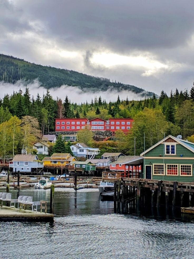 boats are docked at the dock in front of a mountain with houses and buildings on it