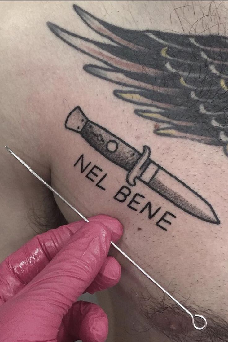 a man with a knife tattoo on his chest and the words nel bene