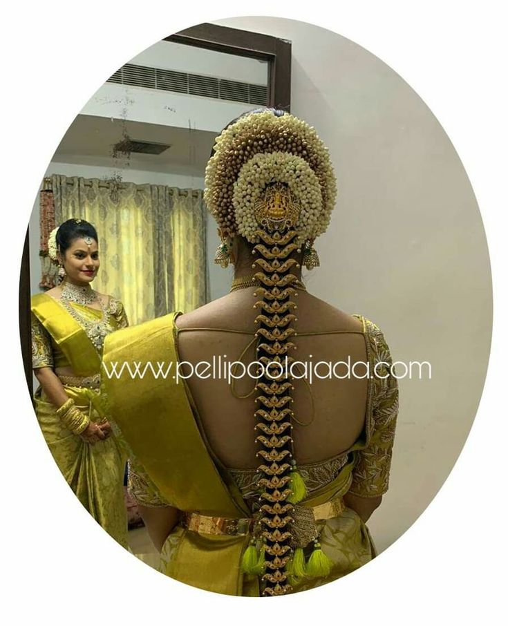 a woman in yellow saree standing next to a mannequin with braids on it