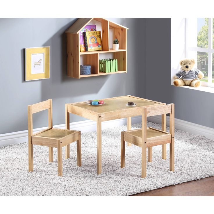 a child's wooden table and chair set with bookshelf in the corner