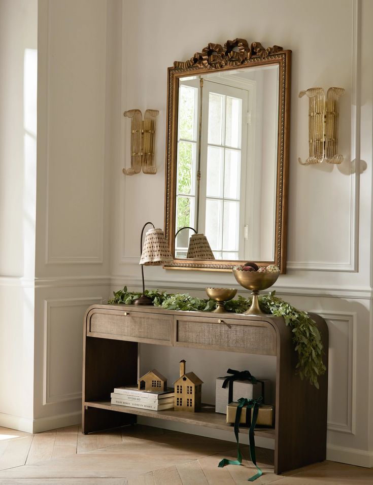 a table with a mirror and some decorations on it in front of a wall mounted shelf