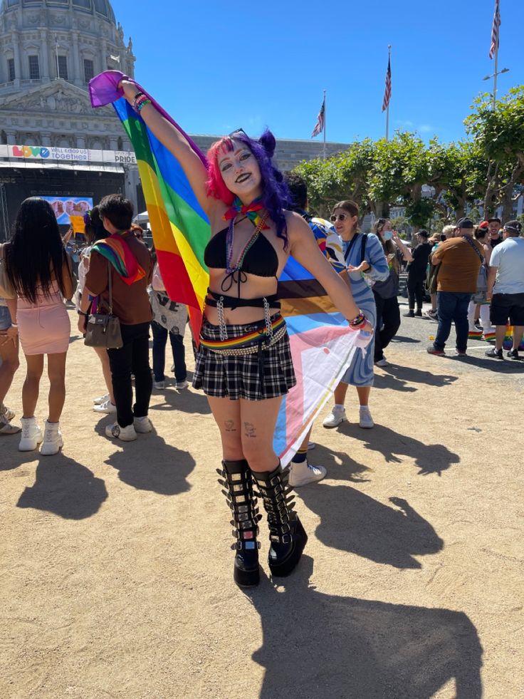 a woman with purple hair holding a rainbow kite in front of a large group of people