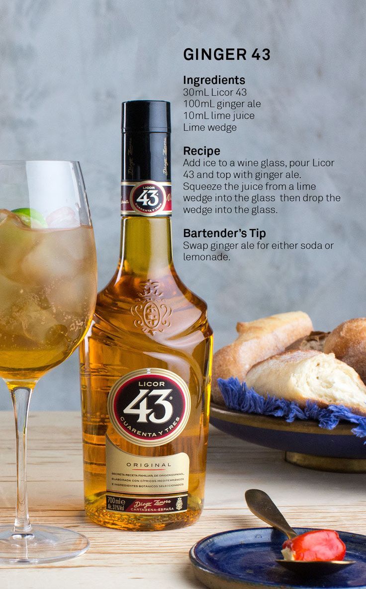 a bottle of alcohol sitting next to a glass filled with liquid and bread on a plate