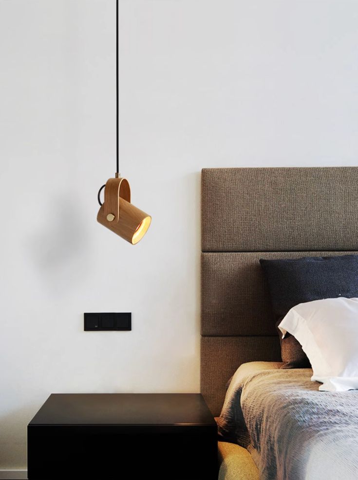 a bedroom with a bed, nightstand and lamp hanging from the ceiling over it's headboard