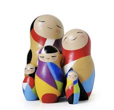 a group of wooden dolls sitting next to each other on top of a white surface