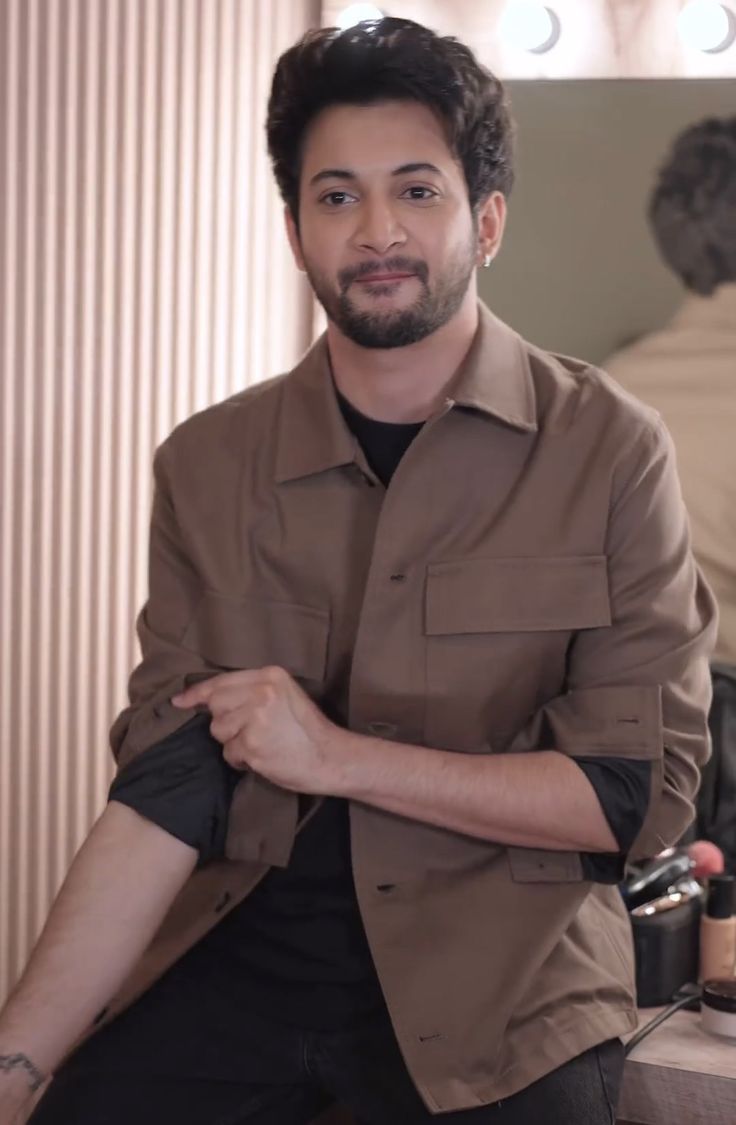 a man sitting in front of a mirror holding his arm