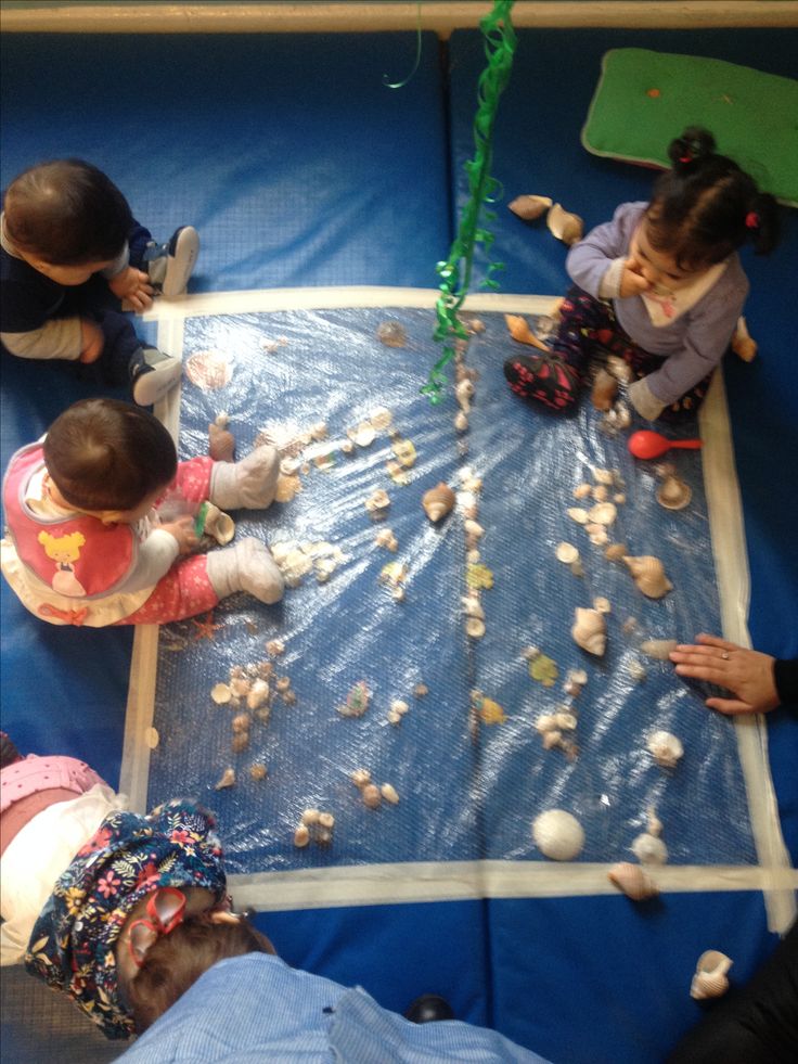 several children are playing with rocks on a blue tarp in an indoor play area