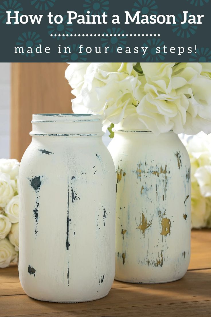 two painted mason jars sitting on top of a wooden table next to white hydrangeas