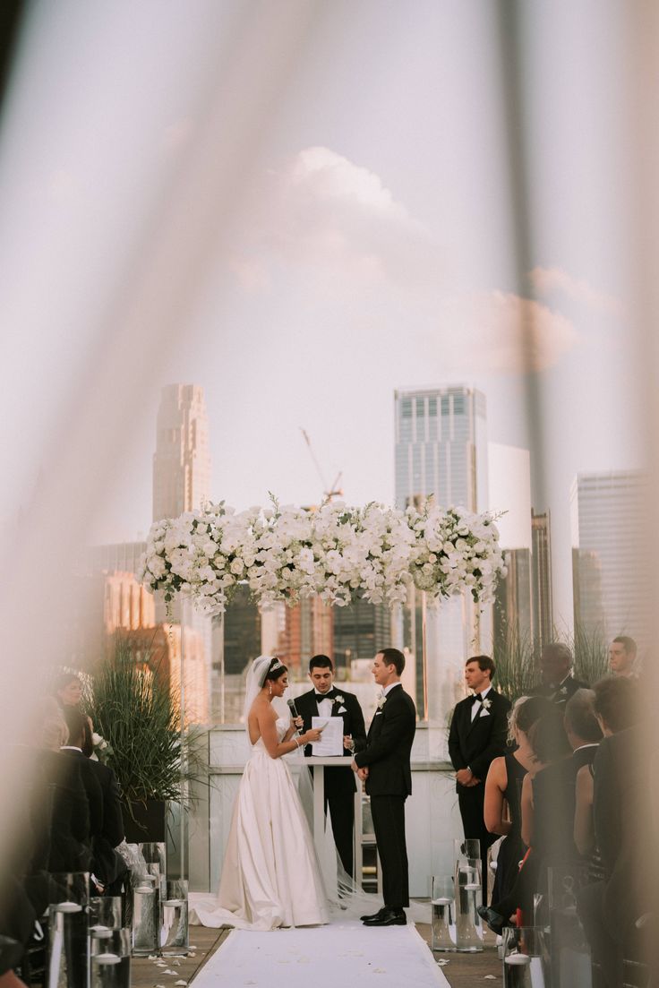 a bride and groom standing at the end of their wedding ceremony on top of a rooftop