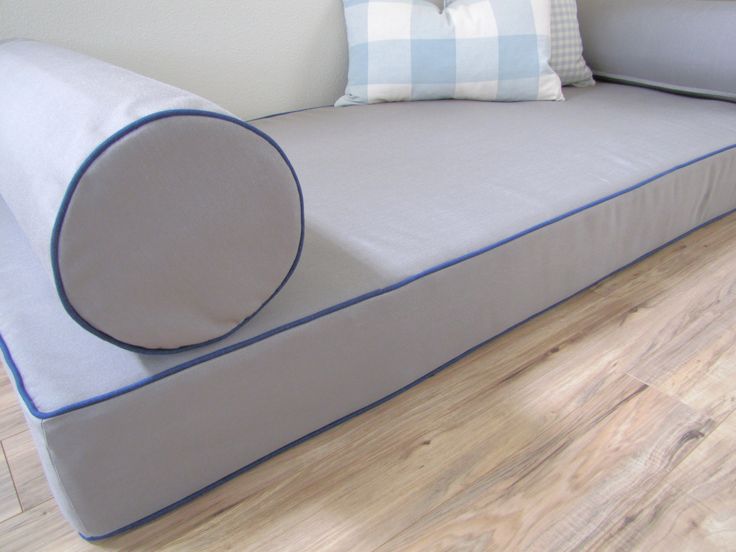 a white couch with blue piping on the back and pillows on it's sides