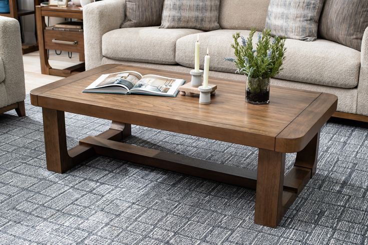 a living room with couches, coffee table and books on the floor in front of it