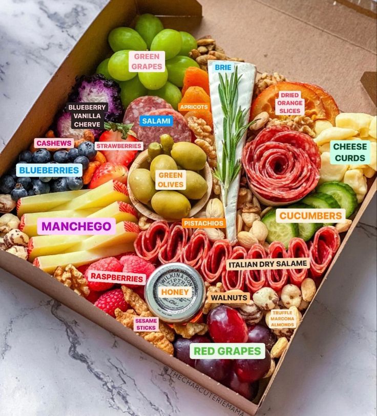 a box filled with lots of different types of food and snacks on top of a marble counter