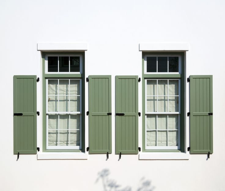 two windows with green shutters on each side