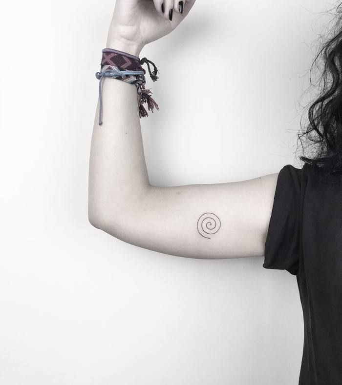 a woman with a tattoo on her arm holding a cell phone up to her ear