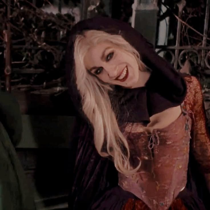 a woman dressed as a witch with long blonde hair and black dress posing for the camera