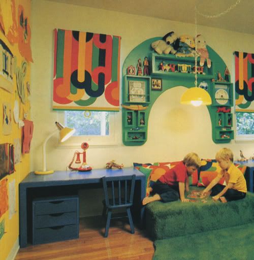 two people sitting on a green couch in a room with colorful wallpaper and artwork