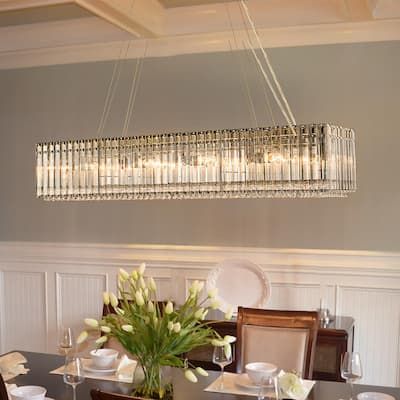 a chandelier hanging from the ceiling over a dining room table with place settings