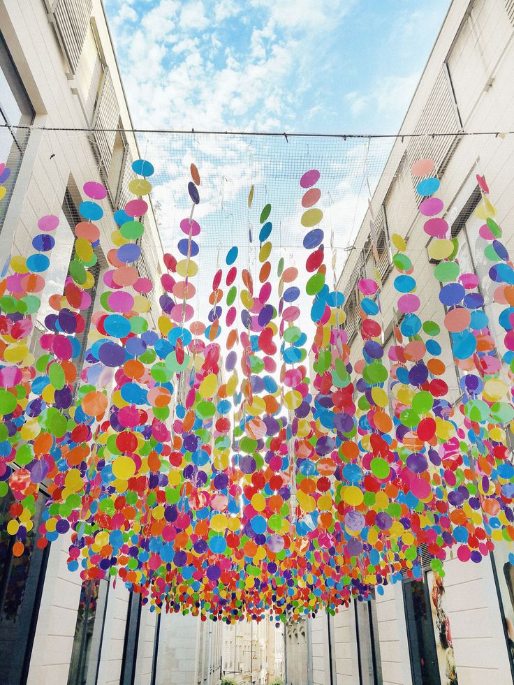 many colorful balloons are hanging from the ceiling