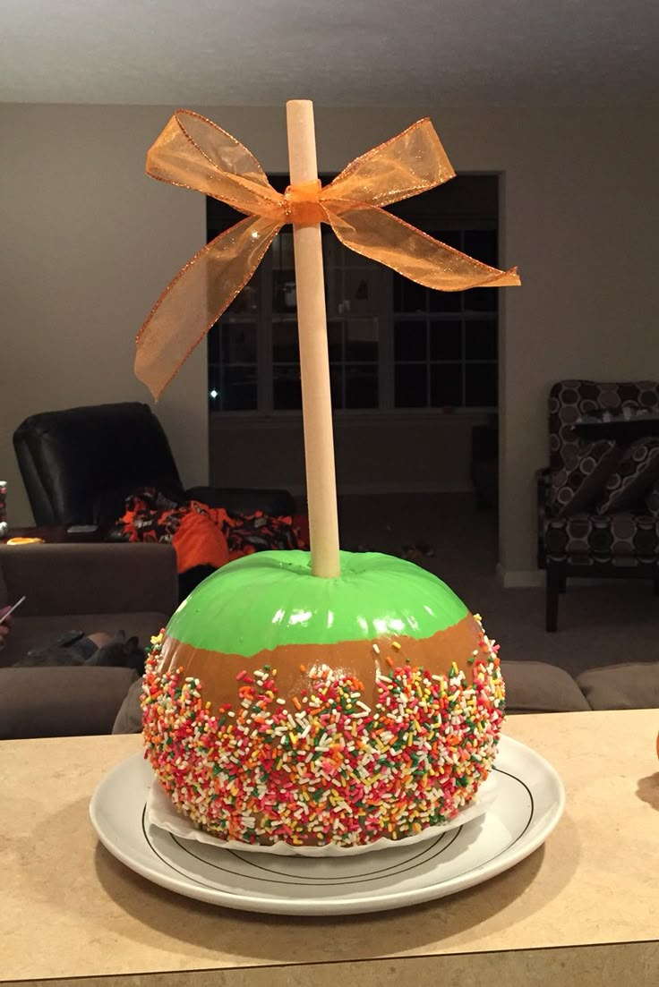 an apple decorated with sprinkles and a bow sitting on top of a plate