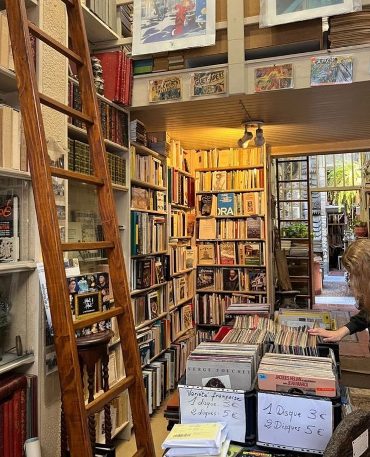 there are many books on the shelves in this room and one ladder is leaning against the wall