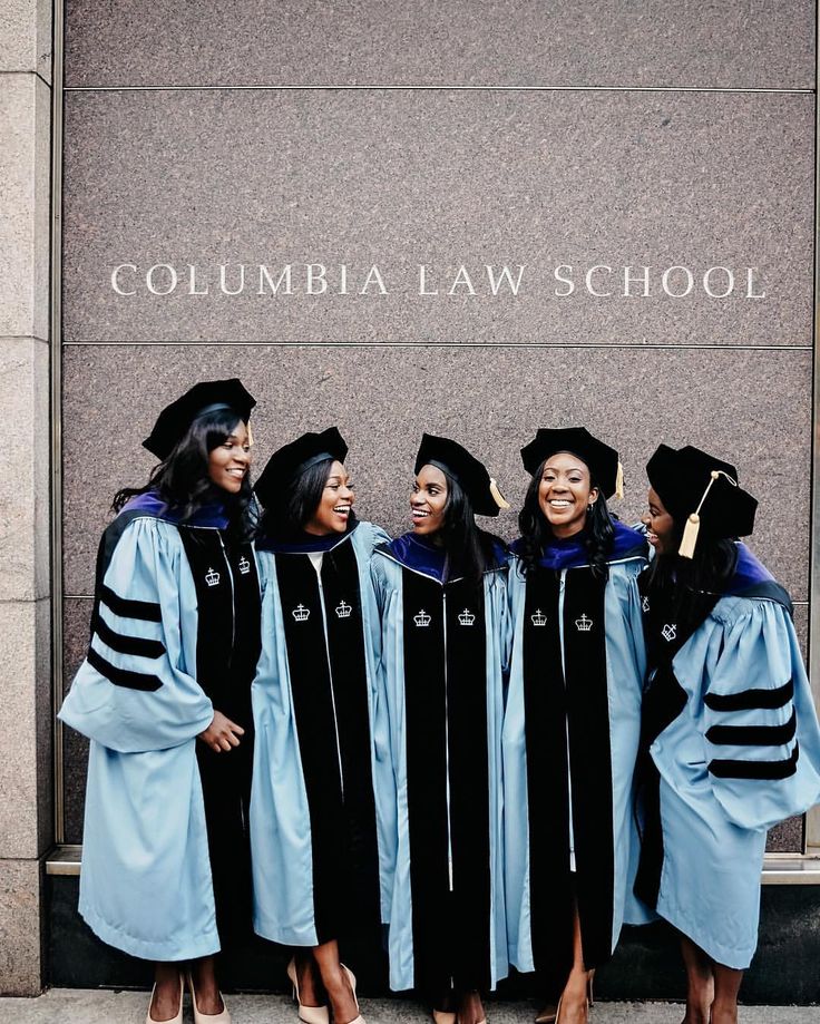 four women in graduation gowns stand together outside the columbia law school