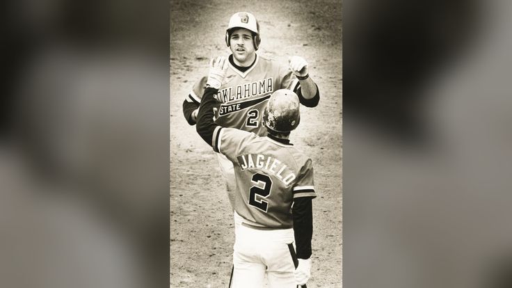 two baseball players standing next to each other on top of a field in black and white