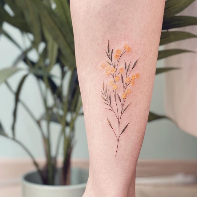 a woman's leg with flowers on it and a potted plant in the background