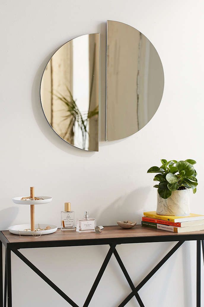 a mirror on the wall above a table with a plant and other items next to it