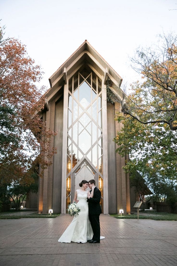 a bride and groom standing in front of a church