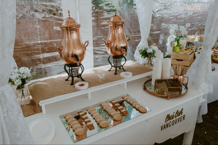 a table with some food on it and two copper teapots sitting next to each other