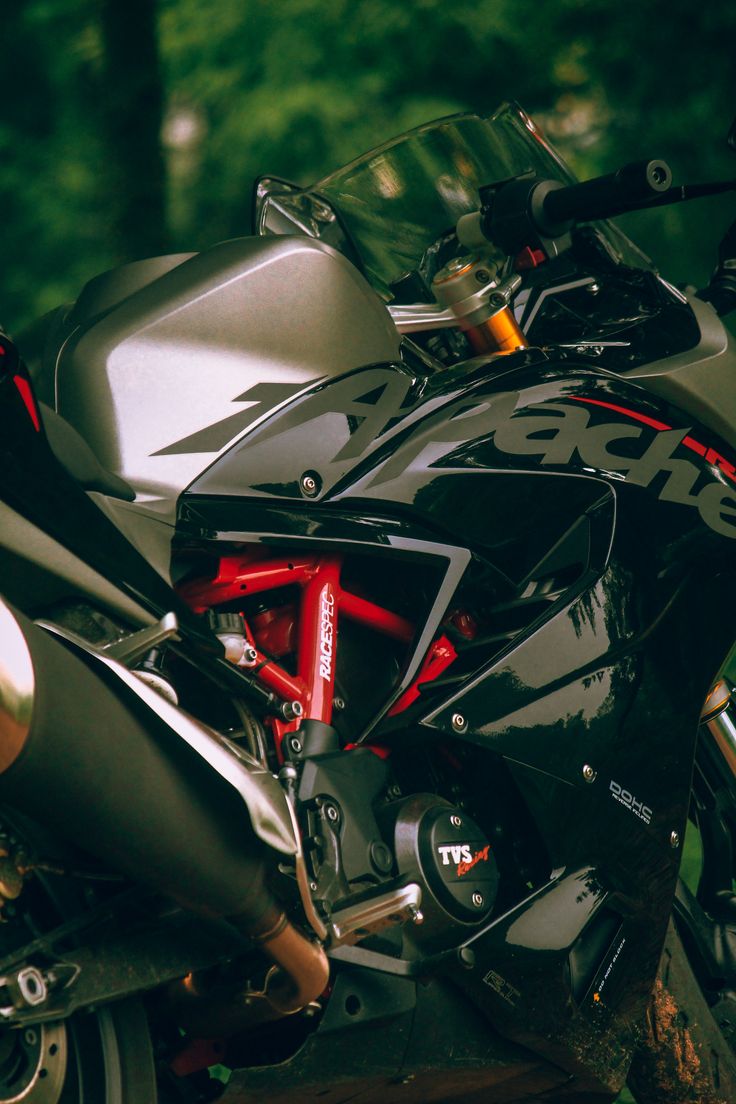 a black motorcycle parked on top of a lush green field next to a wooded area