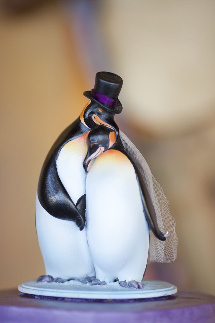 a couple of penguins that are standing on top of a cake plate with a veil over their heads