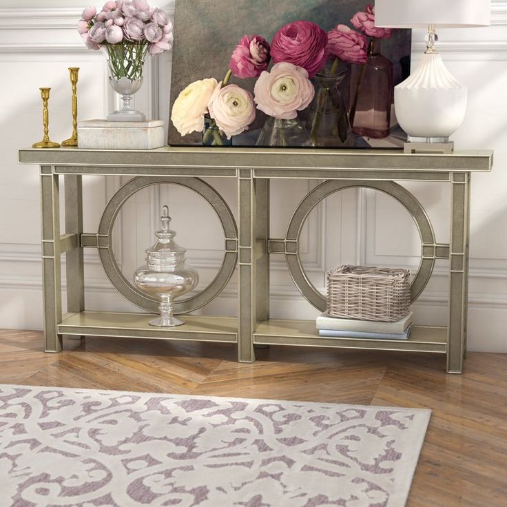 an ornate console table with flowers on top in a white and gold room, next to a rug