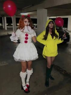 two women dressed in costumes are walking through an empty parking lot with red and white balloons