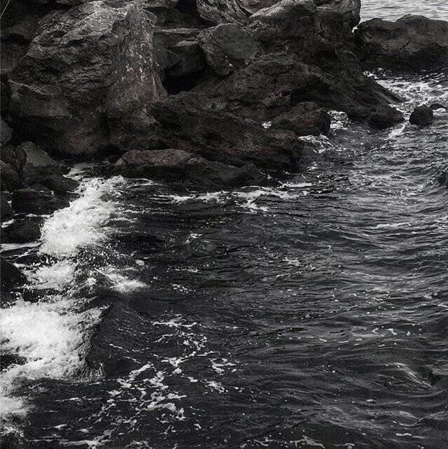 a man standing on top of a rock next to the ocean