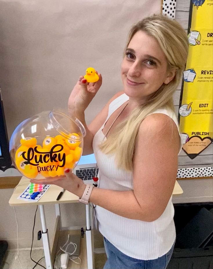 a woman is holding up a gummy ducky in front of a computer screen