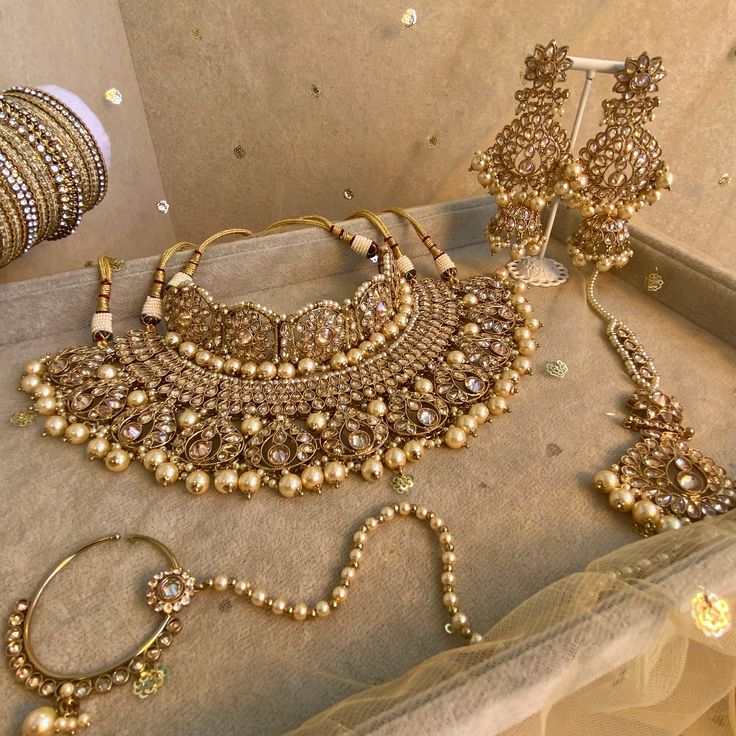 Antique gold bridal choker and necklace set with dazzling champagne zircon crystals and champagne pearl. The perfect wedding jewels.  Comes with choker, necklace, jhumka earrings, tikka and slide type nose ring.  Choker  1.5 inch length adjustable string Necklace 2.5 inch length with double adjustable string.  Earrings 4 Inch including jhumka length x 2 inch width   Tikka 3 inch pendant length plus 4.5 inch chain x 2 inch width  Nose ring which gentle hugs the nostril to secure (LEFT side only) Desi Bridal Jewelry Gold, Pakistani Bride Jewelry, Gold Bridal Jewellery Indian, Nikkah Jewelry, Nose Ring Indian, Pearl Wedding Jewelry Sets, Bridal Jewelry Sets Brides, String Earrings, Indian Bridal Jewelry