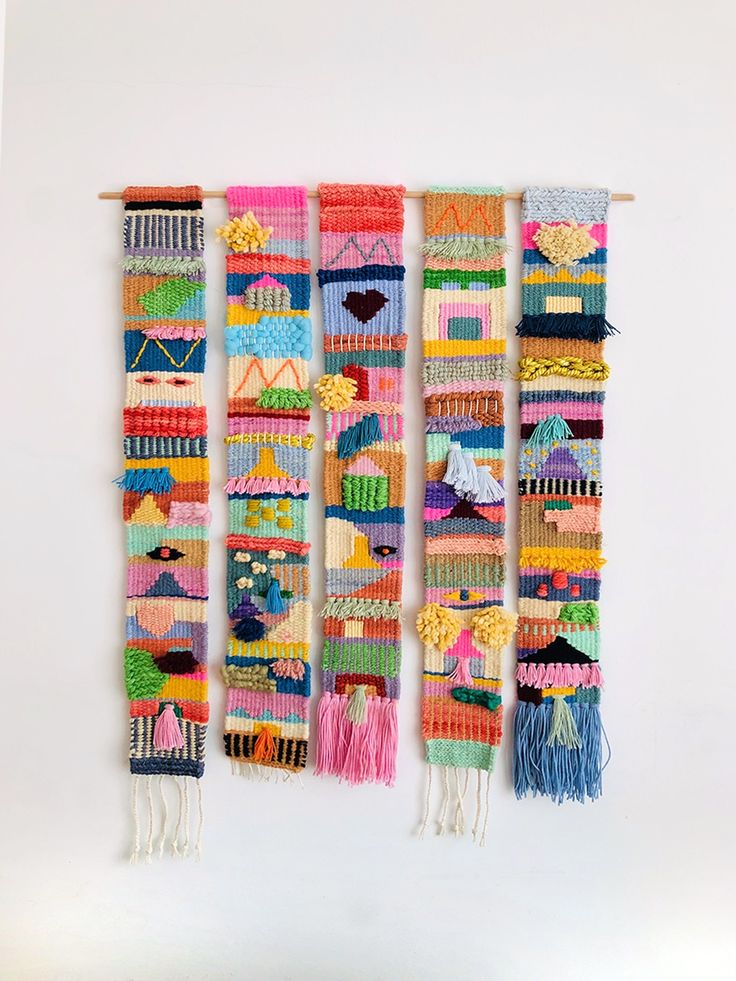 three rows of colorful knitted wall hangings with tassels attached to them