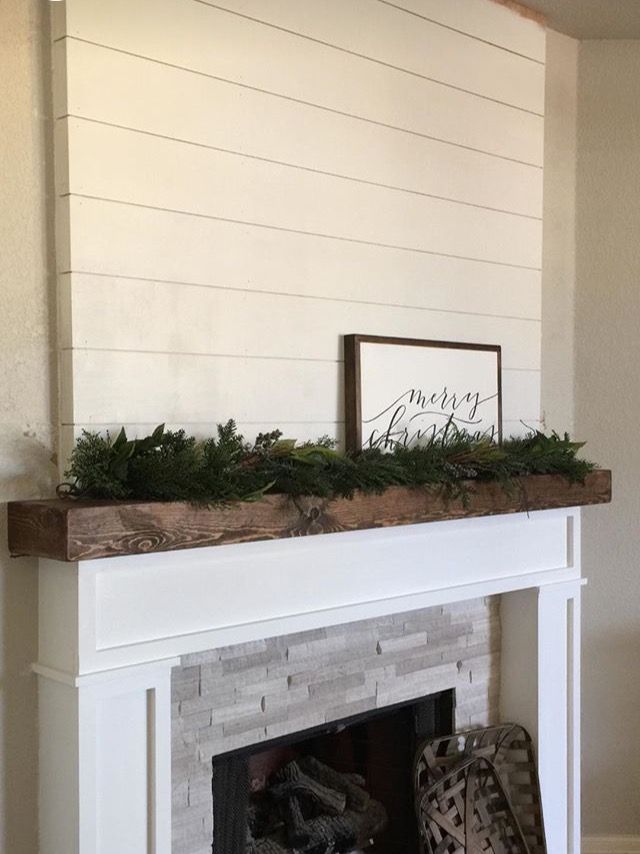 a fireplace with a mantle covered in greenery