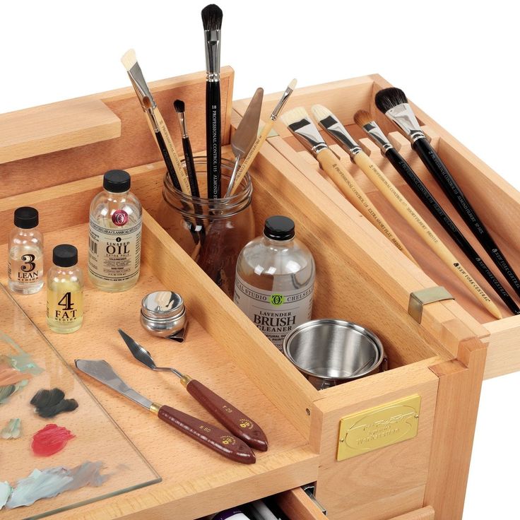 an open drawer with paint, brushes and other crafting supplies