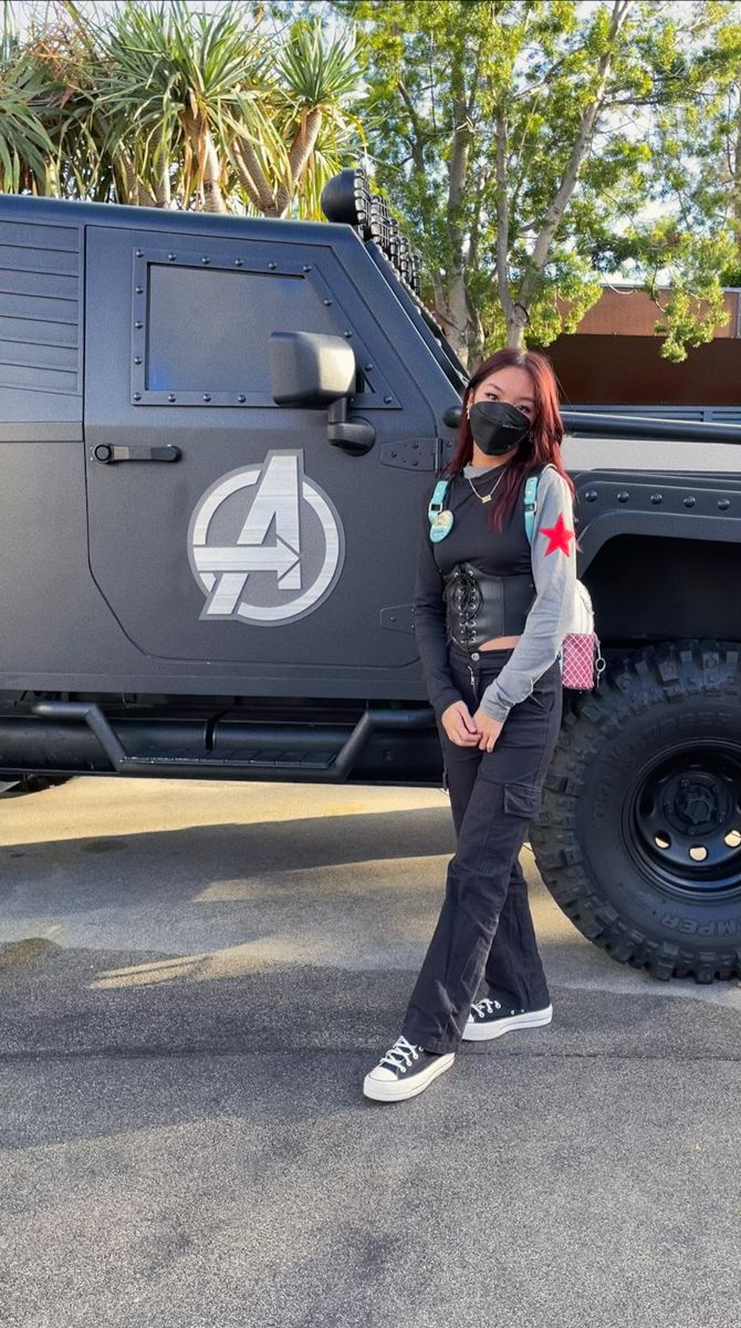 a woman standing in front of a truck with an avengers sticker on it's side