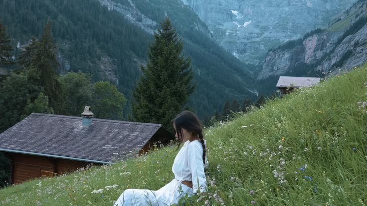 a woman sitting on top of a lush green hillside