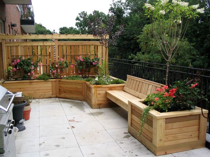 a wooden bench sitting on top of a patio next to flowers and potted plants