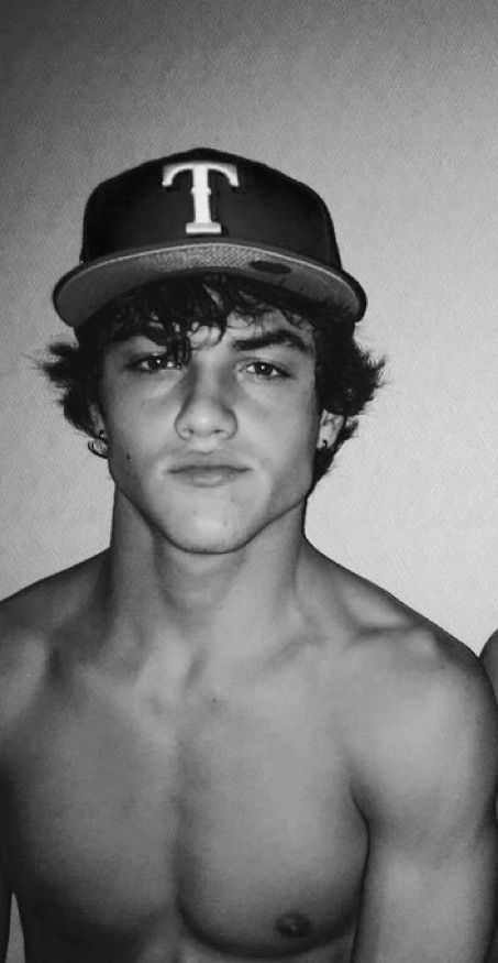 a shirtless young man wearing a baseball cap