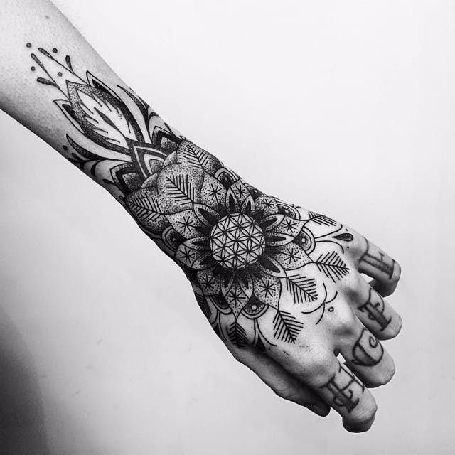 a woman's hand with an intricate tattoo design on the arm and wrist, in black and white