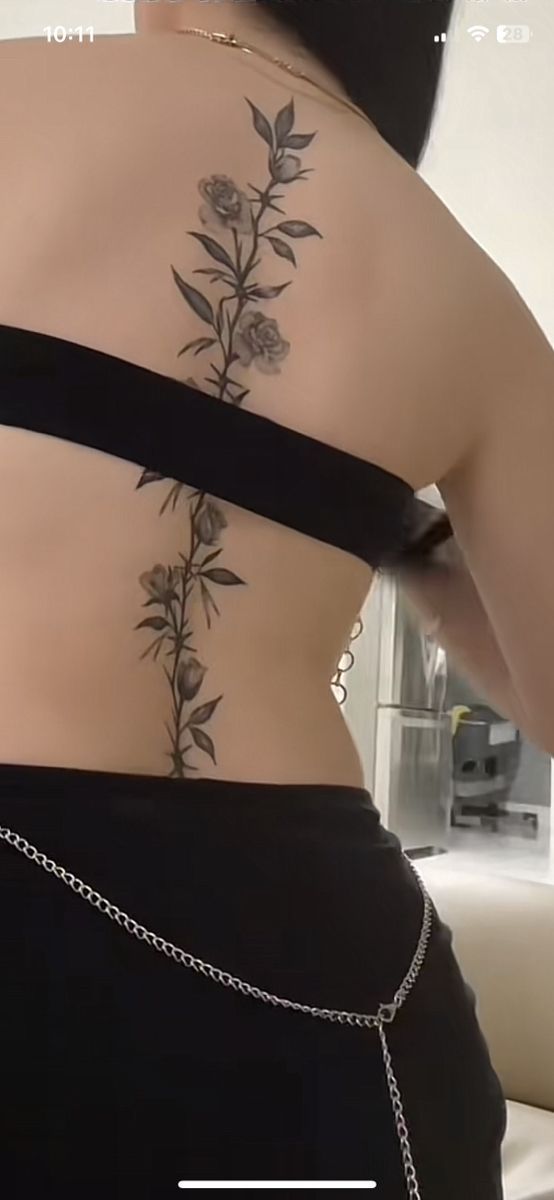 the back of a woman's body with flowers tattooed on her upper and lower back