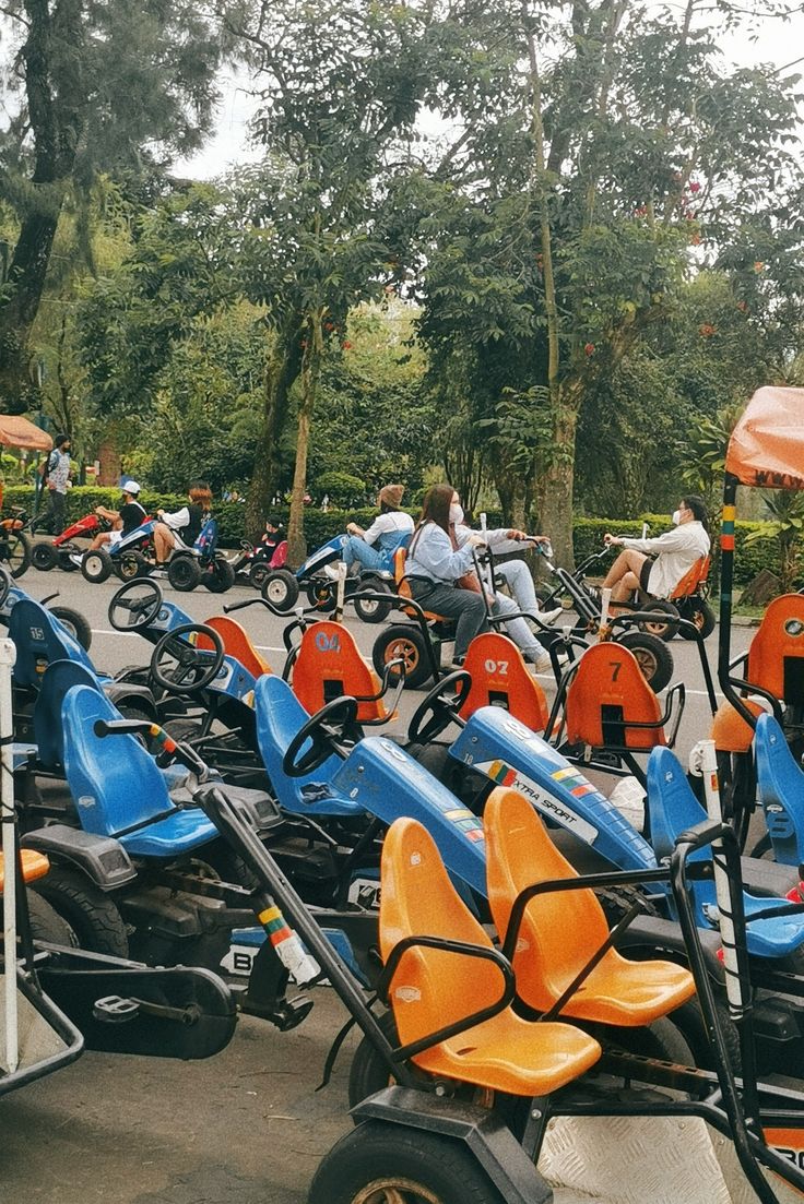 many people are sitting on tricycles in the parking lot and some have umbrellas over them