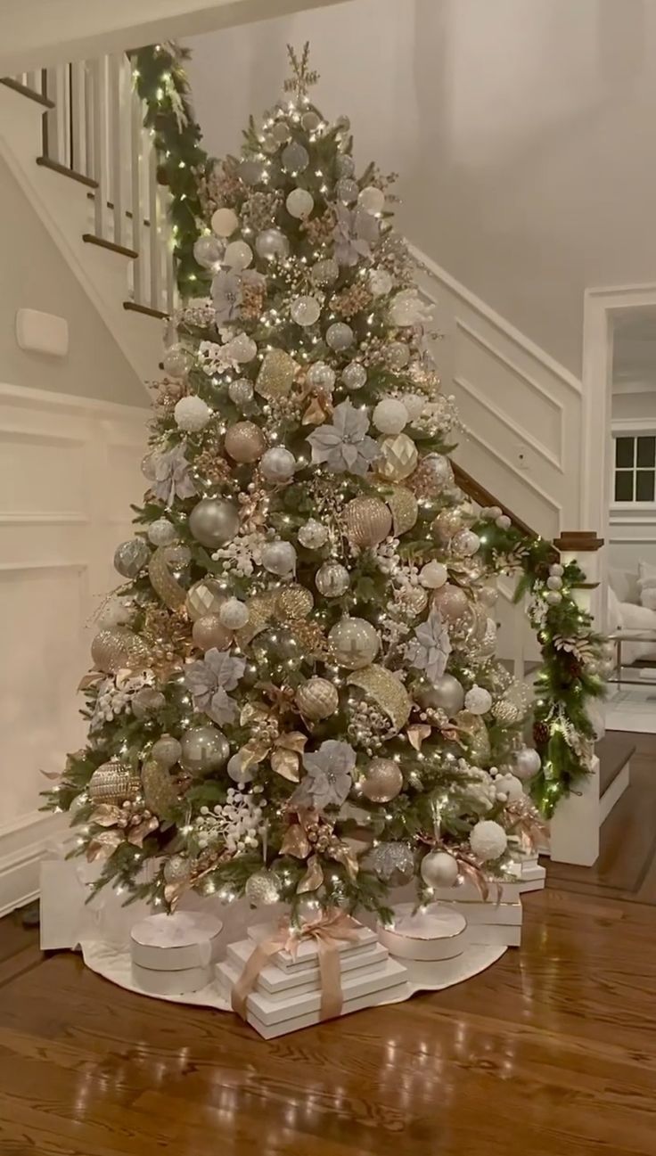 a decorated christmas tree with presents under the stairs