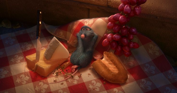 a mouse sitting on top of a table next to cheese and bread with grapes in the background