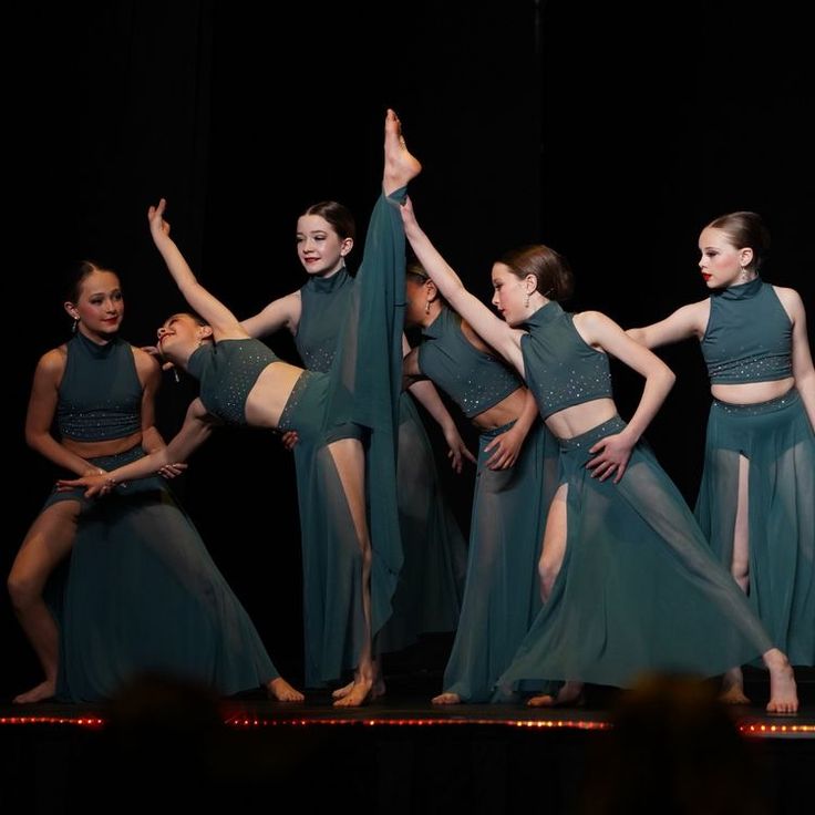 a group of young women standing on top of a stage next to each other holding hands in the air